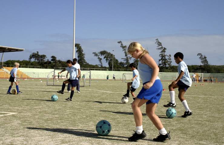 Bambini e bambine giocano a calcio